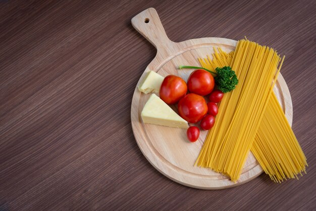 Spaghetti, tomatoes, broccoli and butter on a brown wooden floor