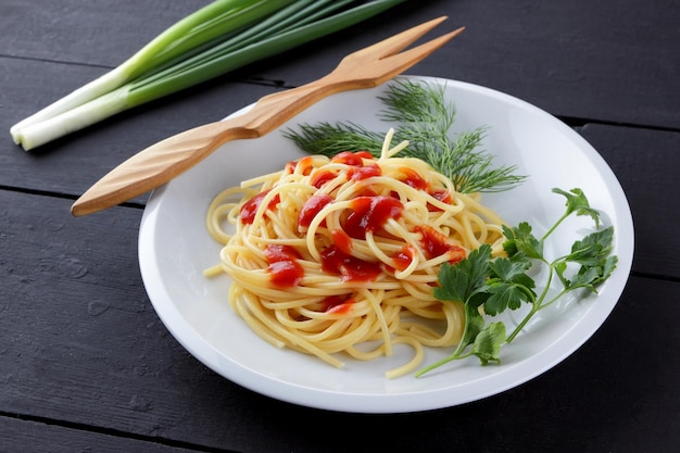 Spaghetti on white plate Pasta with tomato sauce and herbs on dark wooden background Copy space