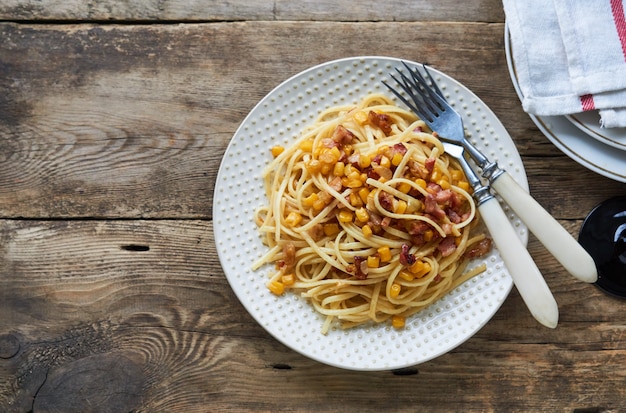 Spaghetti with bacon and corn on a plate