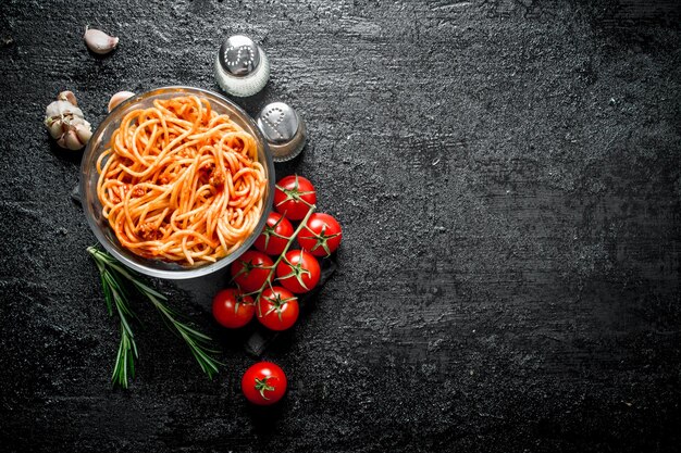 Spaghetti with Bolognese sauce in a glass bowl with tomatoesrosemary and garlic