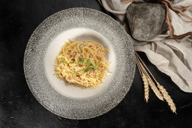 チーズとベーコンのスパゲッティ。デュラム小麦パスタ黒い石のテーブルの上のホットメインコース