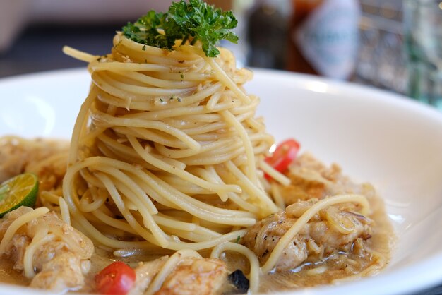 Spaghetti with chicken tomatos and black olives closeup on a plate