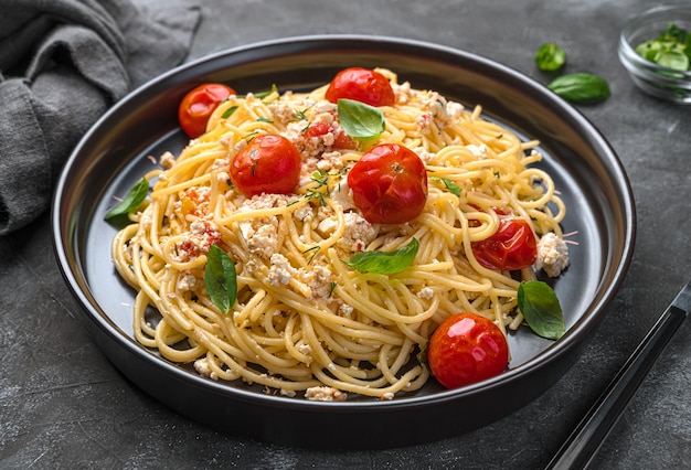Foto spaghetti con formaggio fett pomodorini ed erbe aromatiche primo piano vista laterale