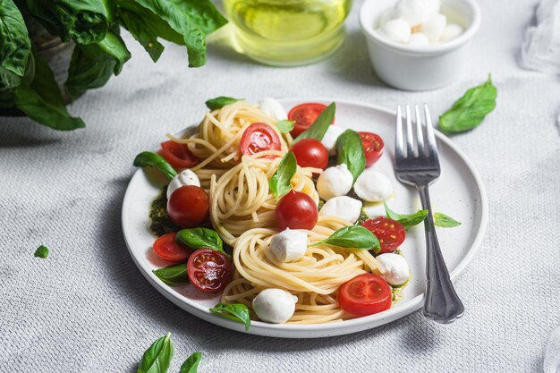 Spaghetti with mozzarella tomatoes basil and pesto sauce Pasta Caprese