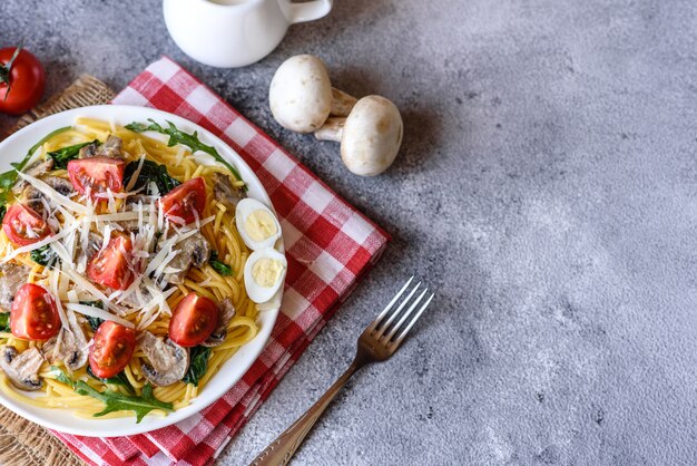 Spaghetti with mushrooms, cheese, spinach, rukkola and cherry tomatoes. Italian dish, Mediterranean culture