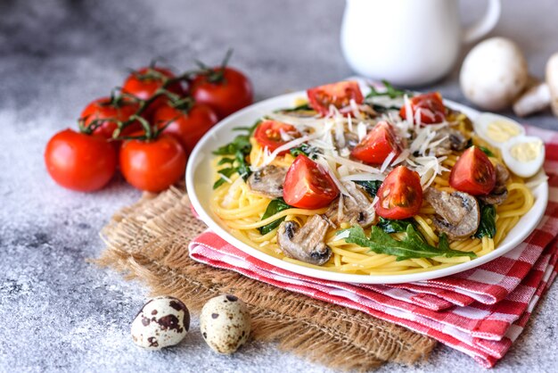 Spaghetti with mushrooms, cheese, spinach, rukkola and cherry tomatoes. Italian dish, Mediterranean culture