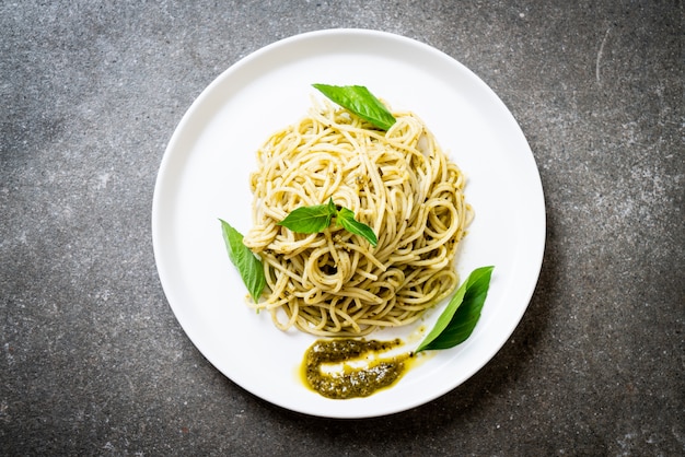 spaghetti with pesto sauce, olive oil and basil leaves.