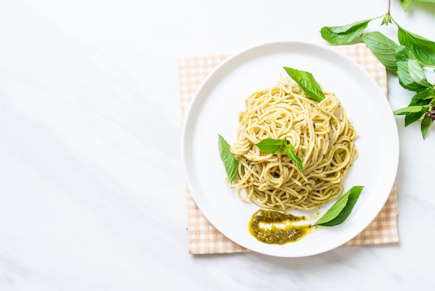 spaghetti with pesto sauce, olive oil and basil leaves.