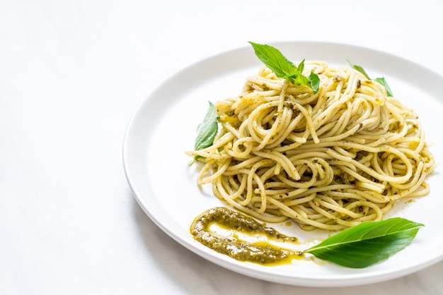 spaghetti with pesto sauce, olive oil and basil leaves.