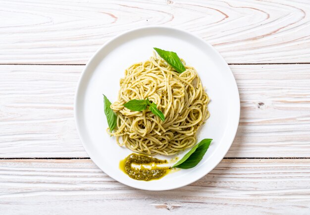 spaghetti with pesto sauce, olive oil and basil leaves.