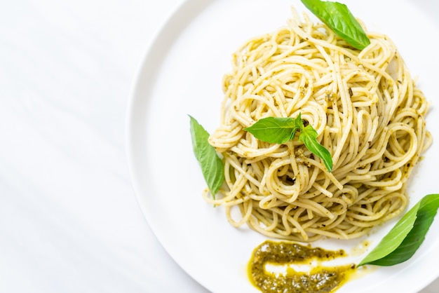 spaghetti with pesto sauce, olive oil and basil leaves.