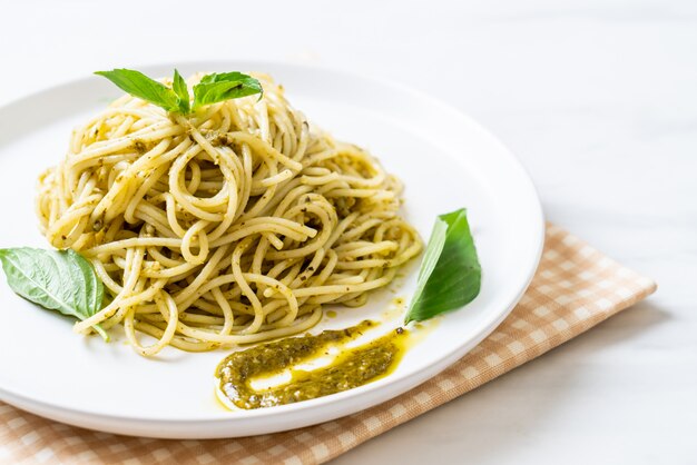 spaghetti with pesto sauce, olive oil and basil leaves.