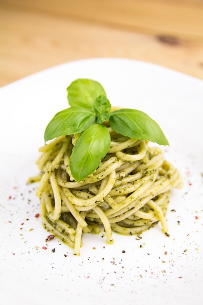 Spaghetti with pesto sauce, white plate, wooden table