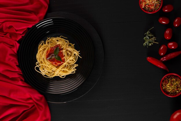 Spaghetti con salsa su un piatto nero in una foto in studio più scura