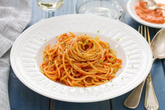 Spaghetti with sauce on white plate on blue wooden table