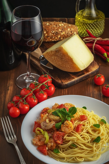 Спагетти с креветками, помидорами черри и специями на деревянных фоне