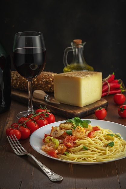 Spaghetti with shrimps, cherry tomatoes and spices on wooden.