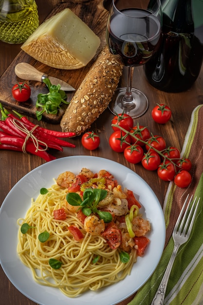 Spaghetti with shrimps, cherry tomatoes and spices on wooden.