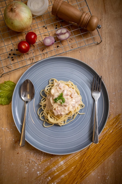 Foto spaghetti con salsa di panna acida in piatto blu