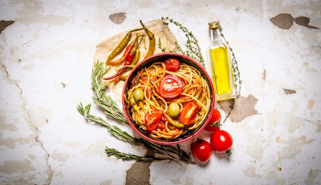 Spaghetti with tomato paste, hot Chili peppers and olive oil.  On rustic background.  Top view