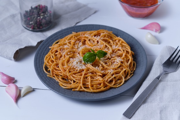 토마토 소스와 파마산 치즈를 곁들인 스파게티. 흰색 나무 테이블에 파스타입니다. 점심으로 이탈리아 요리.