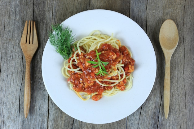 Spaghetti with tomato sauce in a white dish on wooden floor background 