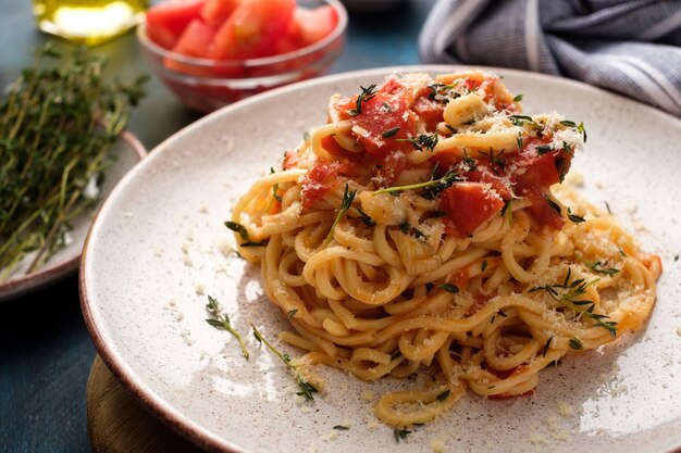 Spaghetti with tomatoes and thyme in a plate on a blue table