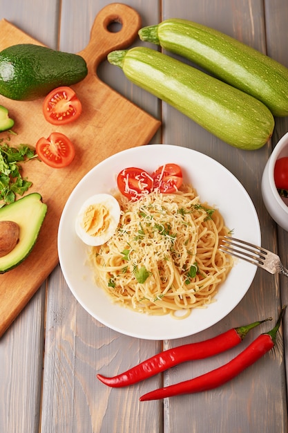 Spaghetti with vegetables, avocado, sweet peppers, cherry tomatoes and parmesan cheese as part of the dish.