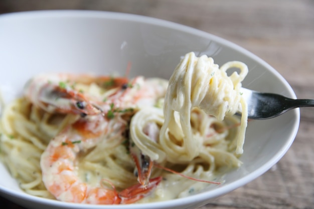 Spaghetti witte saus met garnalen op houten ondergrond