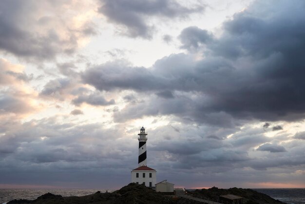 スペイン、バレアレス諸島、メノルカ島、朝の雲に囲まれたファヴァリクス灯台