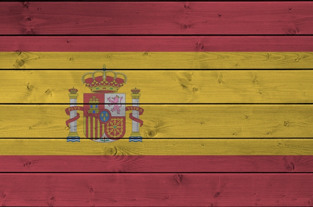 사진 오래 된 나무 벽에 밝은 페인트 색상으로 묘사 된 스페인 깃발. 거친 배경에 질감 된 배너
