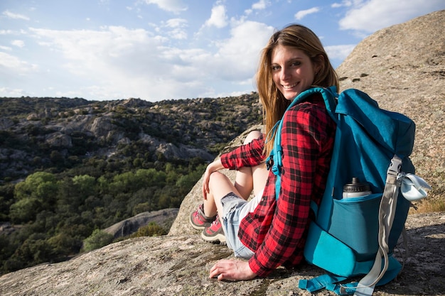 Photo spain, madrid, smiling young woman resting on a rock during a trekking day