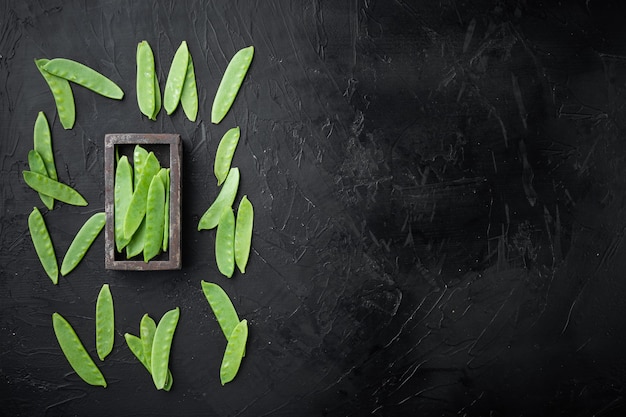 Span peas in wooden box, on black stone