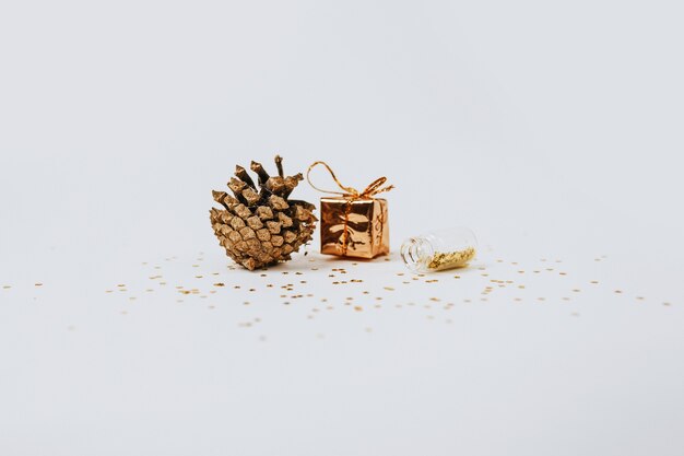 Spangles of gold and silver are scattered from bottles, gift and fir cone and a gift on a white background