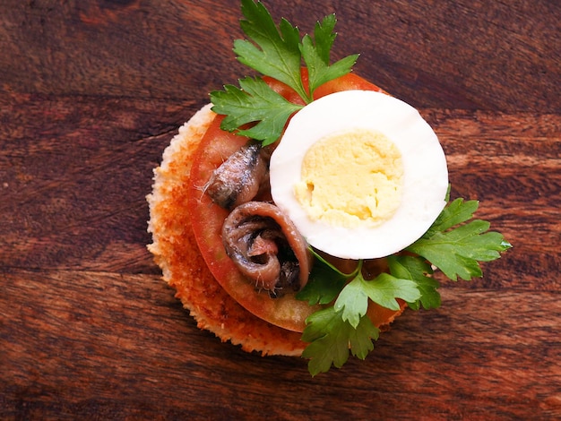 Spanish appetizer tapas with tomato egg and anchovy on a white serving board