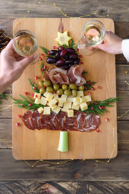 Spanish cheese and sausage board in the shape of a Christmas tree Two people eating Copy space