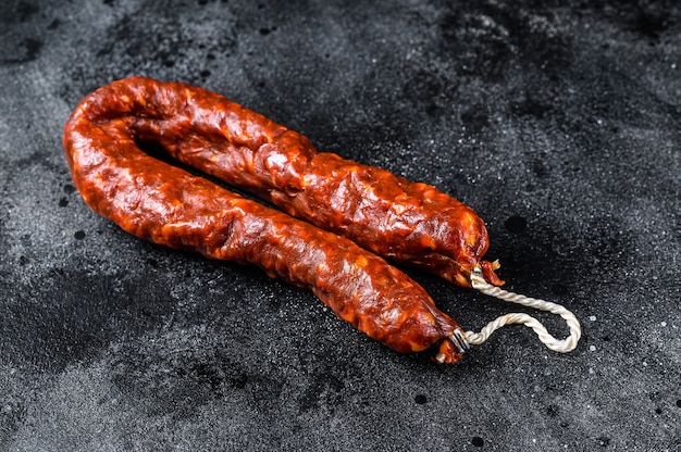 Spanish chorizo pork cured sausage. Black background. Top view.