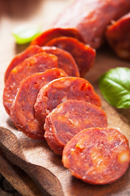 Spanish chorizo sausage with basil on chopping board