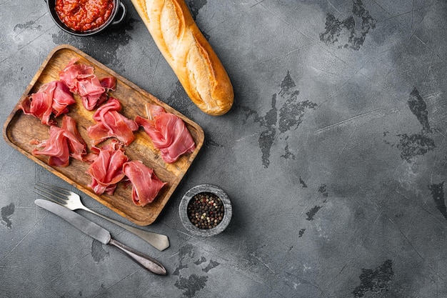 Jamon spagnolo di carne fredda impostato su sfondo grigio tavolo in pietra vista dall'alto piatto con spazio per la copia del testo