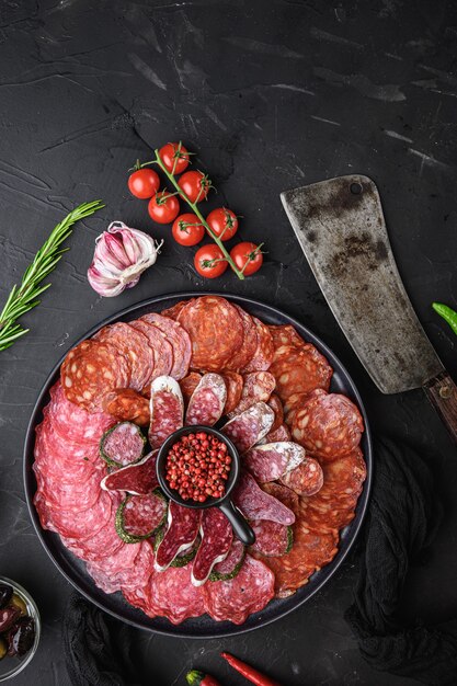 Spanish cold meat plate, chorizo, fuet, lomo,longaniza and salchichon on balck table, top view.