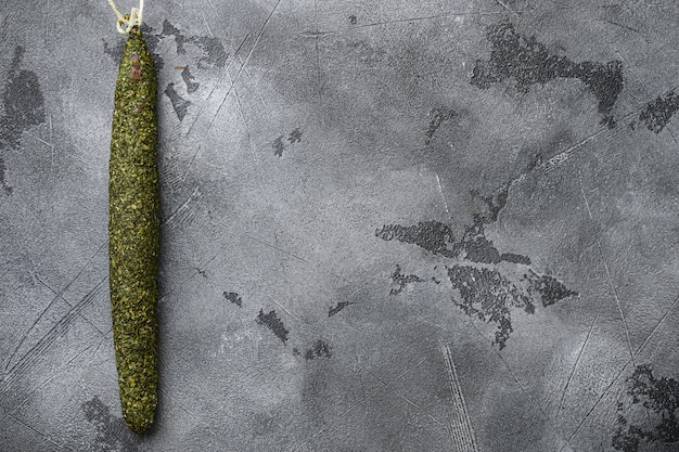 Spanish dry salami sausage fuet in herbs on grey textured background