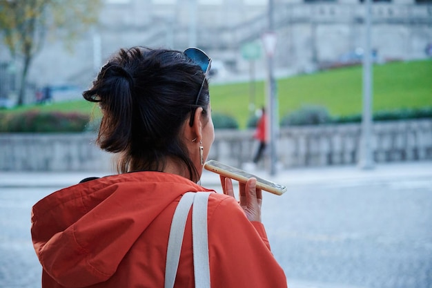 A Spanish female is making a voice message in a street