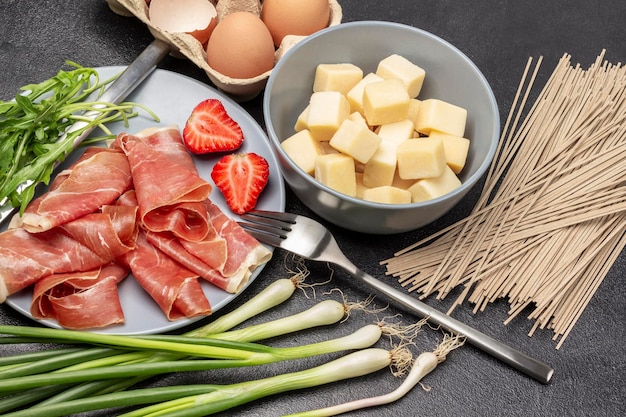 Spanish jamon with strawberries and arugula on gray plate Eggs in a box