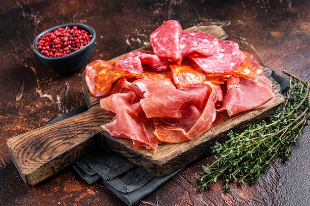 Spanish meat tapas - salami, jamon, choriso cured sausages. Dark background. Top view.