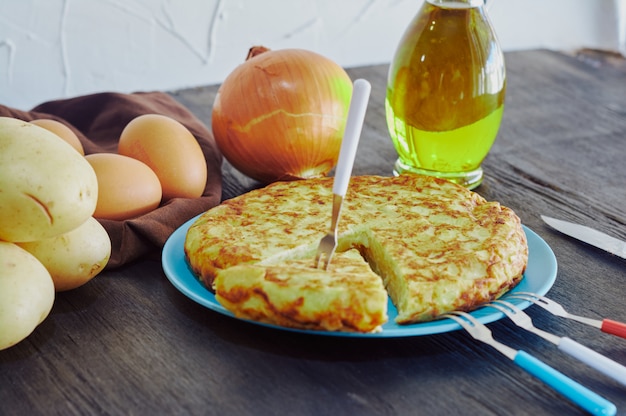 Foto frittata spagnola con patate, uova e cipolla, accompagnata da olio d'oliva