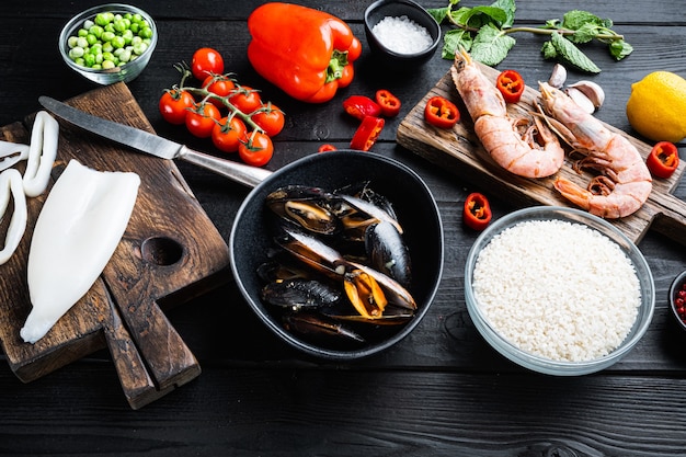 Ingredienti della paella spagnola con riso, gamberi, seppie e cozze sul tavolo di legno nero, foto di cibo.