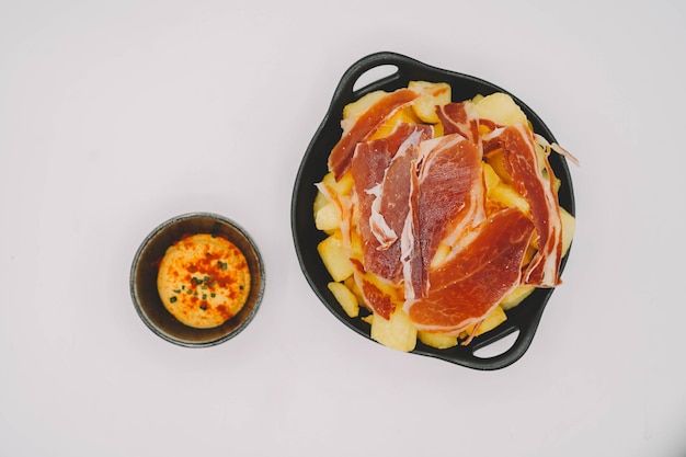 Spanish patatas bravas ration with Iberian cured ham.