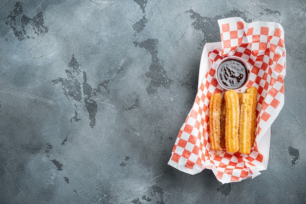 Spanish porras. Spanish food like spanish churros with chocolate and caramel

 in paper tray, on gray background, top view flat lay with space for text, copyspace