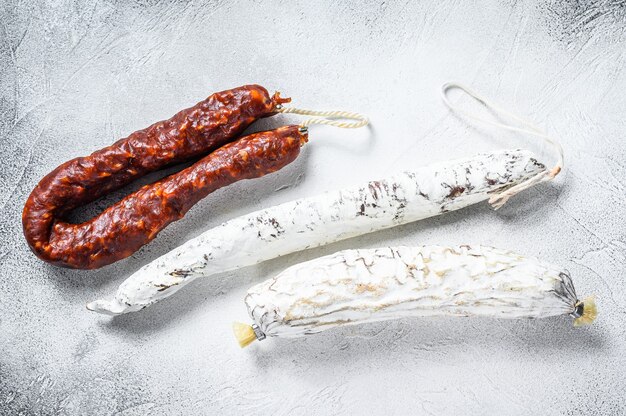 Spanish salami, fuet and chorizo sausages on a kitchen table. White background. Top view.