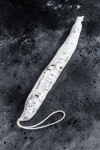 Spanish salami fuet sausage on a kitchen table. Black background. Top view.